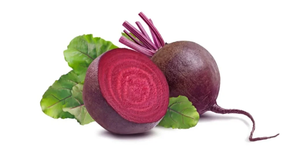 A freshly cut beetroot with vibrant red interior, surrounded by green leaves and another whole beet in the background.