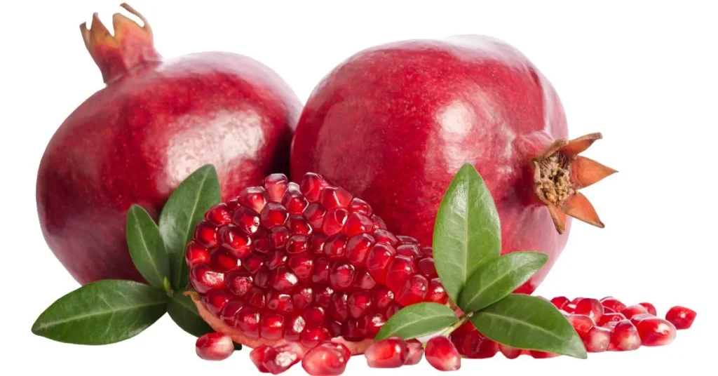 Two vibrant red pomegranates with green leaves, one cut open to reveal juicy seeds, displayed on a white background.