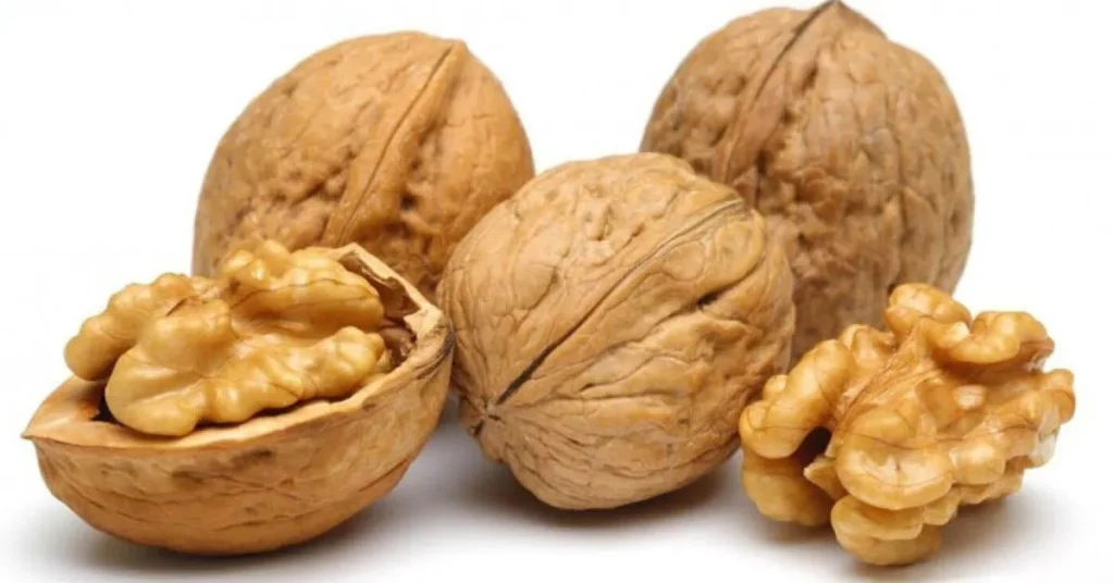 Four walnuts, two whole and two halves, displaying their textured brown shells and rich, light brown flesh.