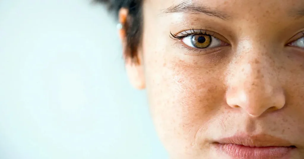 Close-up of a person's ear with dark hair, set against a blurred light background, highlighting the texture and color contrast.